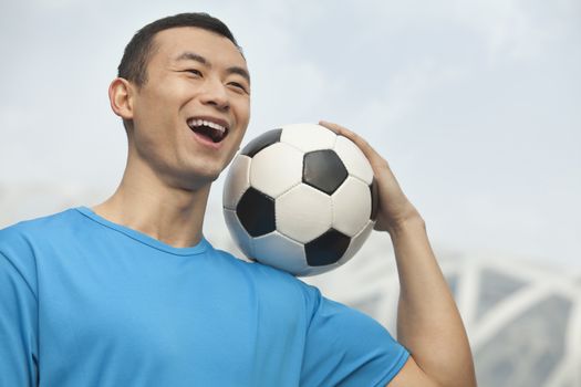 Young man holding soccer ball, Beijing