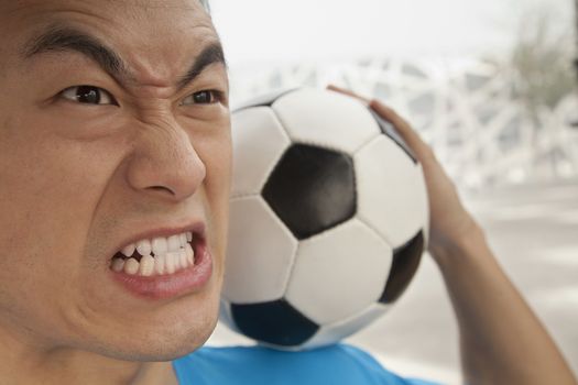 Close up of angry young man holding a soccer ball
