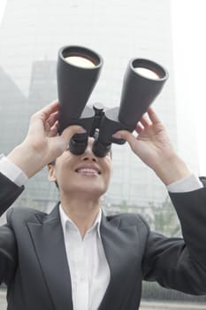 Smiling Businesswoman Using Binoculars Outside in Beijing, Looking Up