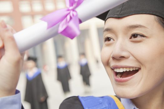 Close Up of Young Female Graduate Smiling and Holding Diploma