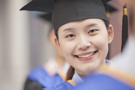 Close Up of Female Graduate Student Standing in a Row of Graduates