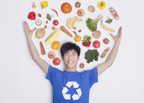 Young man with fresh fruit and vegetables, studio shot