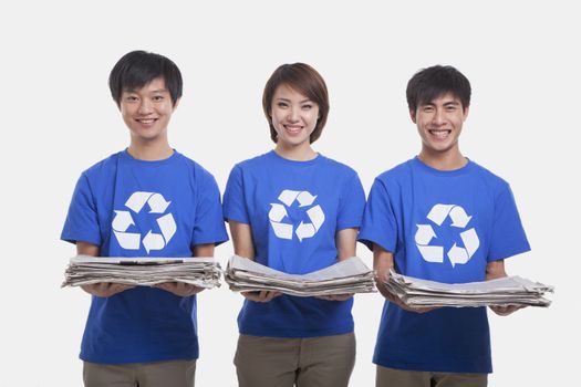 Three young people carrying newspapers, studio shot