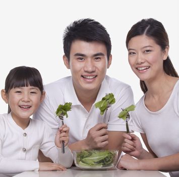 Family sharing a salad, studio shot