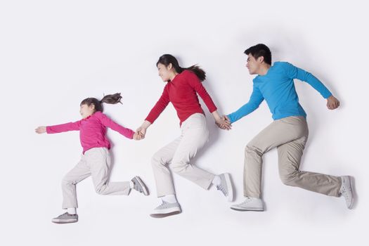 Family holding hands and imitating running, studio shot