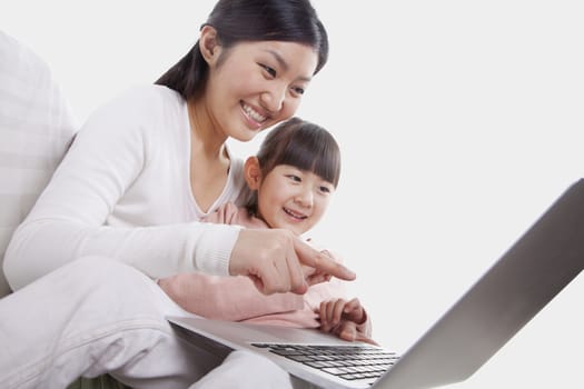 Mother and daughter sitting on sofa using a laptop, tilt