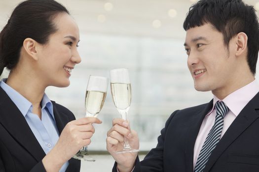 Young business man and woman toasting with champagne flutes