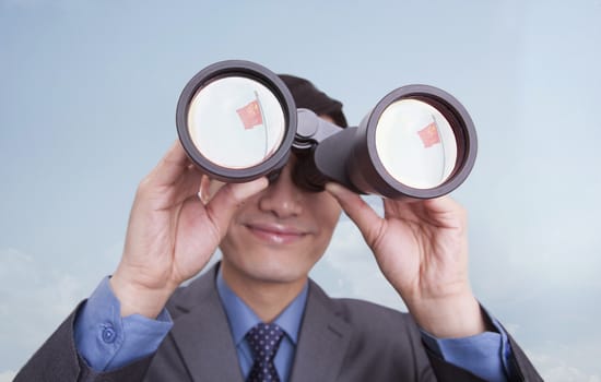 Young businessman looking through binoculars, reflection of Chinese flag, Beijing