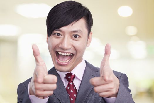 Young businessman making pistols with his fingers at camera, portrait