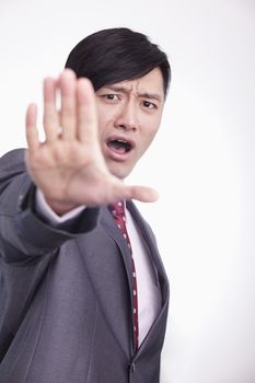 Young businessman with hand raised in stop gesture, studio shot