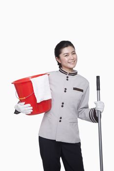 Young female caretaker with bucket and mop, studio shot