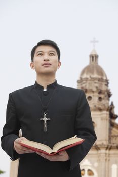 Young Priest Looking to Sky in Front Of Church
