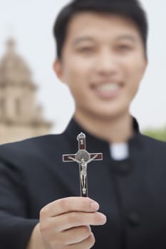 Young Priest Holding Crucifix, Looking at Camera