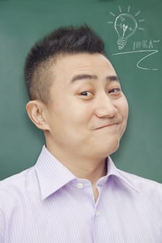 Portrait of young man with an idea in front of a blackboard