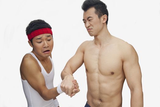 One young man beating another at arm wrestling, studio shot