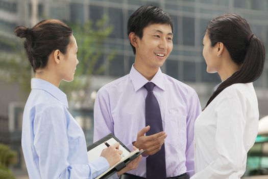 Three young business people talking outdoors, Beijing