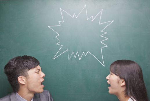 Two young people yelling at each other in front of blackboard