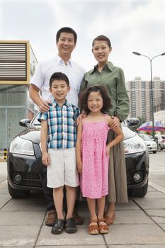 Family smiling in front of the car, portrait