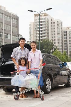 Family with shopping cart standing next to the car