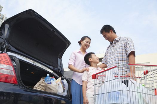 Family talking next to the car with shopping bags