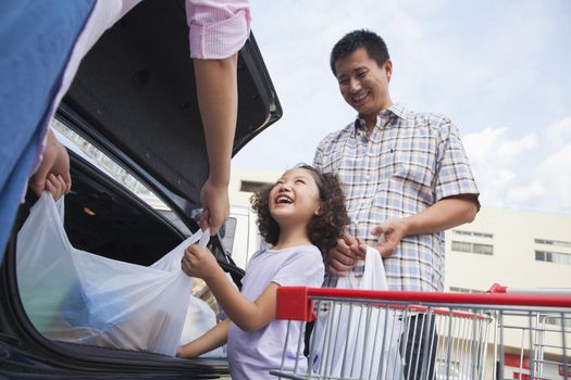 Family talking next to the car with shopping bags