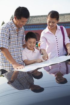 Family standing next to the car and looking at the map