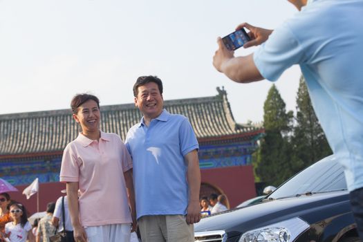 Son taking photo of his parents with his cell phone