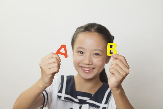 Girl smiling and holding plastic letters, Studio