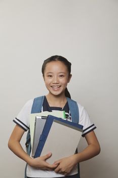 Girl smiling and holding bunch of notebooks and digital tablet, Studio