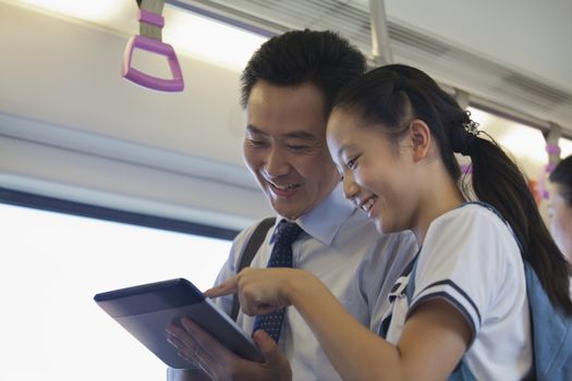 Father and daughter watching a movie in the subway