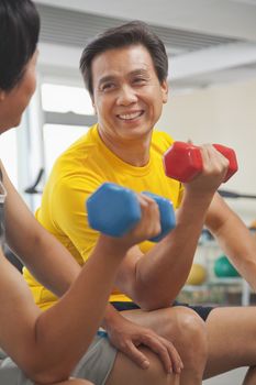 Two mature men lifting weights in the gym