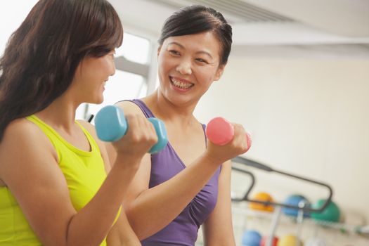 Two mature women lifting weights in the gym