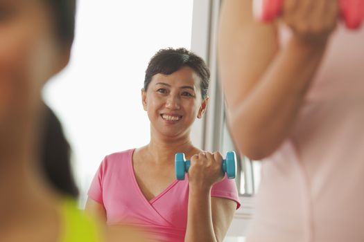 Mature women lifting weights in the gym