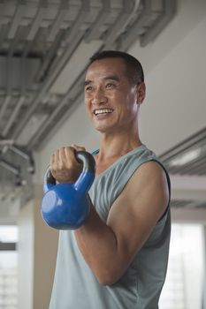 Mature man lifting weights in the gym