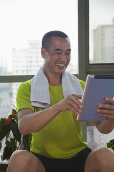 Mature man looking at his digital tablet in the gym
