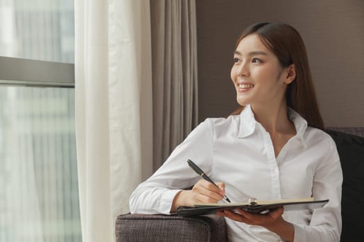 Businesswoman taking notes and looking at the window