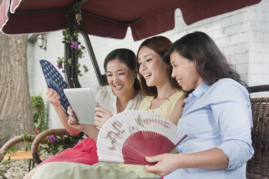 Three Women with Fans and Tablet Outdoors