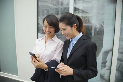 Young businesswomen looking at their cell phones