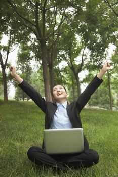 Young businesswoman sitting in the park and stretching