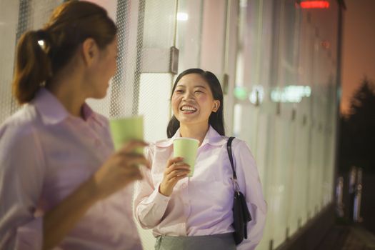 Young businesswomen smiling and drinking coffee outdoor