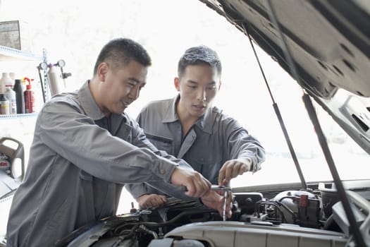 Two Garage Mechanics Working on Engine