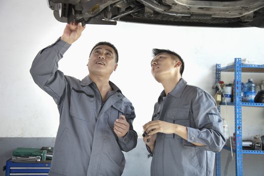 Two Mechanics Looking at Underside of a Car