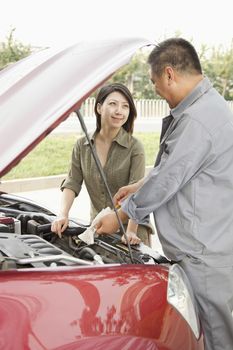 Woman and Mechanic Working on Car