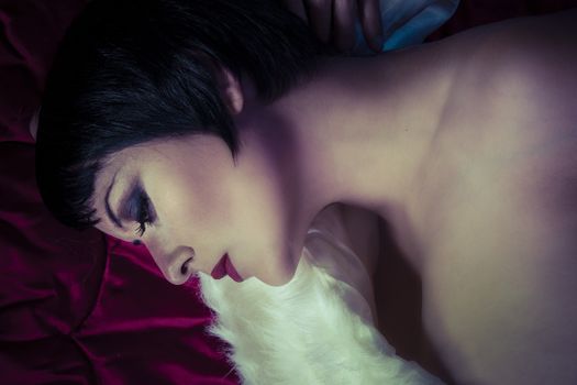 Sensual brunette woman lying naked on red silk, detail