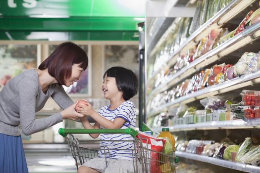 Mother and daughter holding apple, shopping for groceries, Beijing