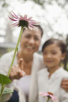Grandmother and granddaughter looking at flower in garden