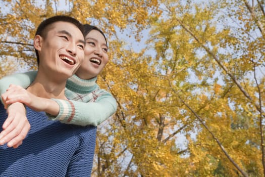 Young couple piggyback in park