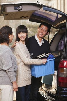 Family unpacking minivan for college, Beijing