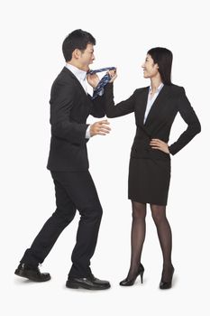 Businesswoman pulling businessman's tie