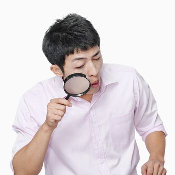 Young man looking through magnifying glass